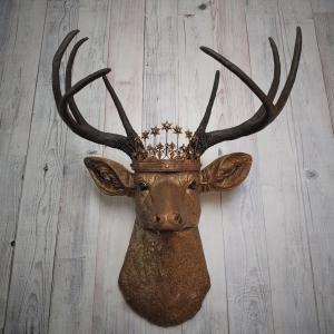 Faux taxidermy deer head that's been painted antique gold with chestnut brown accenting. The antlers are chestnut brown and a vintage inspired Santos star crown/tiara sits arop the deers head.