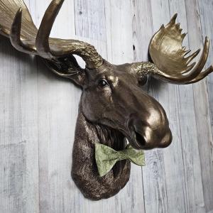 faux taxidermy moose head wall mount, painted dark copper with antique gold accents and antique gold antlers. A green bow tie accents the neck.