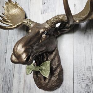 faux taxidermy moose head wall mount, painted dark copper with antique gold accents and antique gold antlers. A green bow tie accents the neck.