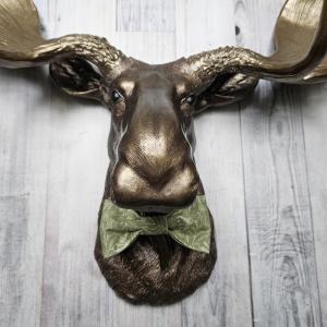 faux taxidermy moose head wall mount, painted dark copper with antique gold accents and antique gold antlers. A green bow tie accents the neck.