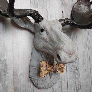 Faux taxidermy  moose head, painted pale grey with bronze accenting. Antlers are painted rubbed bronze. A removable sock monkey print bow tie accents the moose's neck.