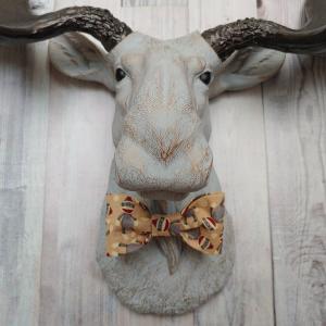 Faux taxidermy  moose head, painted pale grey with bronze accenting. Antlers are painted rubbed bronze. A removable sock monkey print bow tie accents the moose's neck.