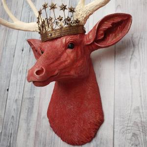 Faux taxidermy deer head, painted red with antique white antlers with a bronze Santos crown atop its head.