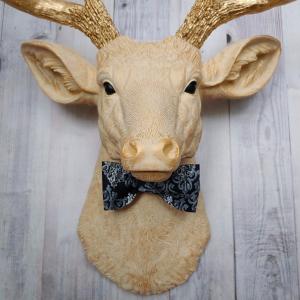 Faux taxidermy deer head painted cream with gold accenting and gold antlers. A fabric bow tie accents the neck, fabric color is dark blue multi with lighter blue and white