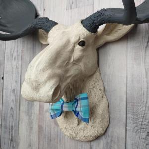 Antique white moose head with slate grey antlers and a blue plaid bow tie