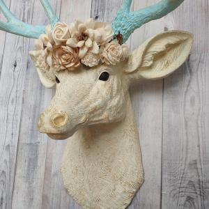 Faux taxidermy deer head, painted antique white with spa blue and gold accents. Antlers are spa blue with gold accents. A removable floral crown made out of cream sola flowers rests atop the deer head