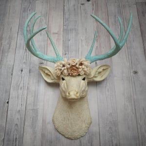 Faux taxidermy deer head, painted antique white with spa blue and gold accents. Antlers are spa blue with gold accents. A removable floral crown made out of cream sola flowers rests atop the deer head.