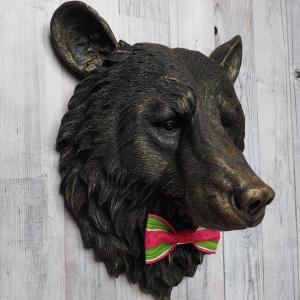 Faux taxidermy bear head wall mount, painted black with gold accenting. A watermelon print fabric bow tie accents the bears neck.