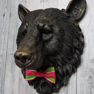 Faux taxidermy bear head wall mount, painted black with gold accenting. A watermelon print fabric bow tie accents the bears neck.
