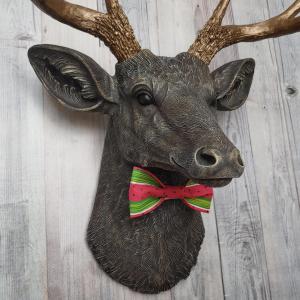 Faux taxidermy deer head painted chestnut brown and accented with antique white and antique gold. The antlers have been painted antique gold and the eyes have been painted black.Watermelon print fabric bow tie accents the deers neck.