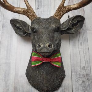 Faux taxidermy deer head painted chestnut brown and accented with antique white and antique gold. The antlers have been painted antique gold and the eyes have been painted black.Watermelon print fabric bow tie accents the deers neck.