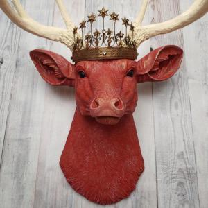 Faux taxidermy deer head, painted red with antique white antlers with a bronze Santos crown atop its head.