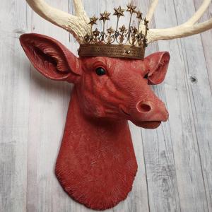 Faux taxidermy deer head, painted red with antique white antlers with a bronze Santos crown atop its head.