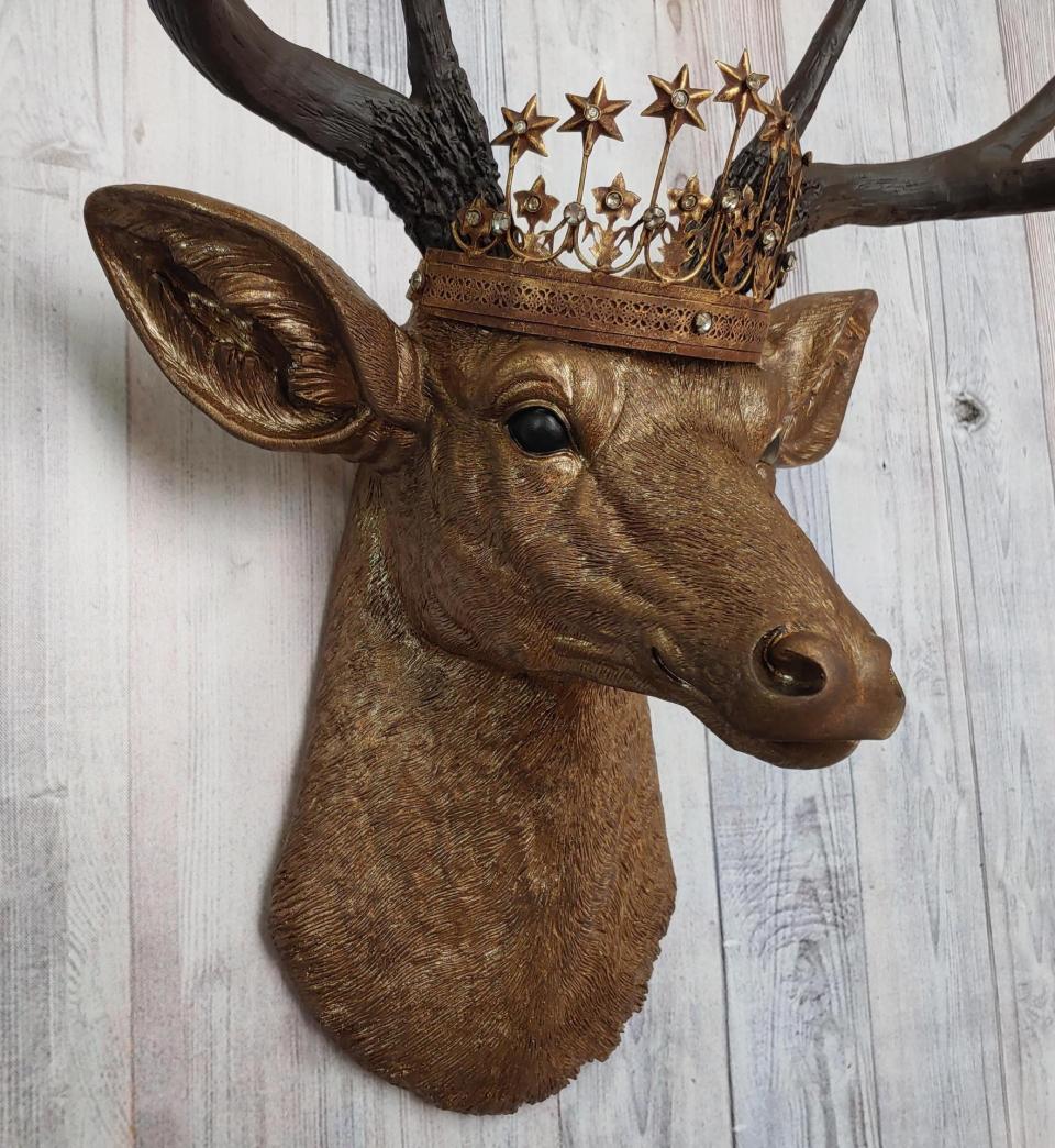 Faux taxidermy deer head that's been painted antique gold with chestnut brown accenting. The antlers are chestnut brown and a vintage inspired Santos star crown/tiara sits arop the deers head.