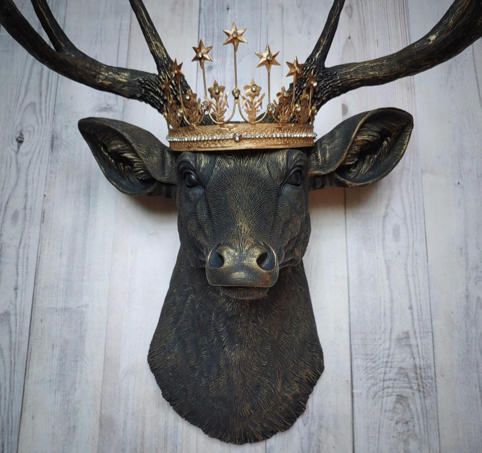 Faux taxidermy deer head wall mount painted black with gold accents. A gold Santos star crown accents the top of the deers head.