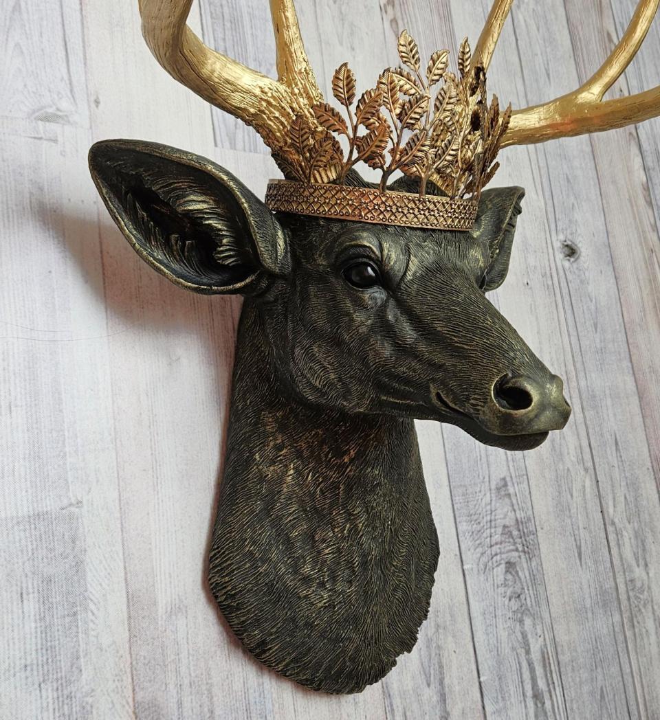 faux taxidermy deer head wall mount in black with gold accenting and gold antler. A gold metal work crown rests atop the deers head.