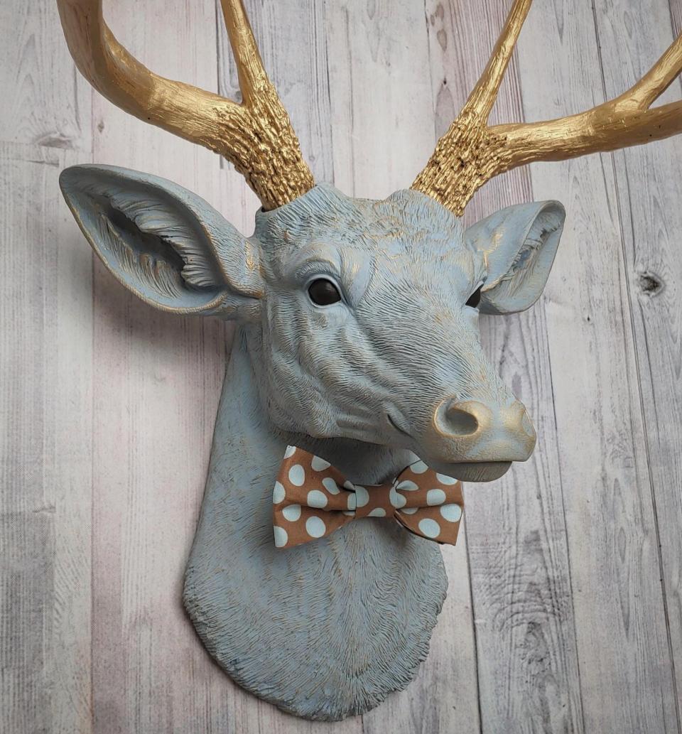Faux taxidermy deer head painted winter blue with gold antlers and a removable brown and blue polka dot bow tie