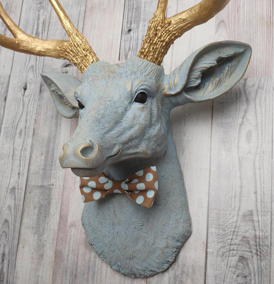 Faux taxidermy deer head painted winter blue with gold antlers and a removable brown and blue polka dot bow tie