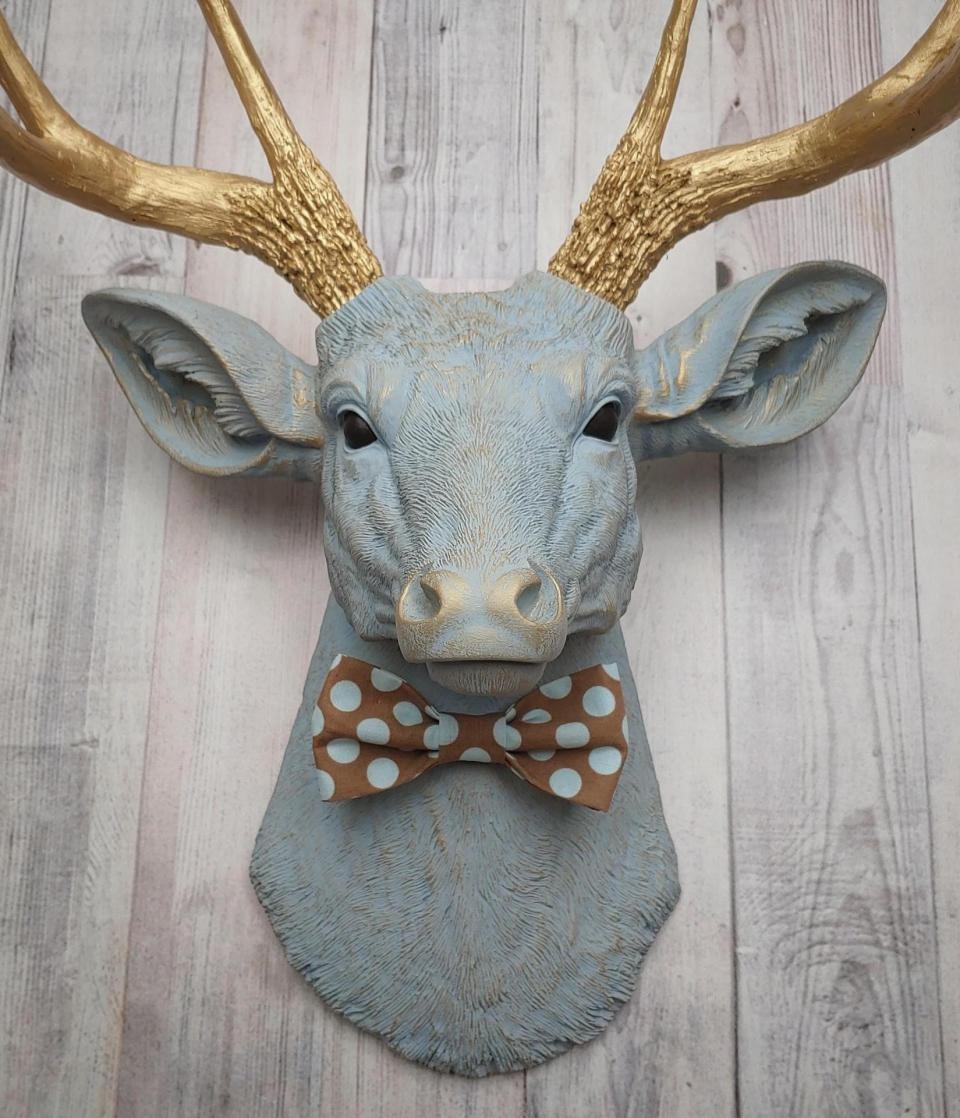 Faux taxidermy deer head painted winter blue with gold antlers and a removable brown and blue polka dot bow tie
