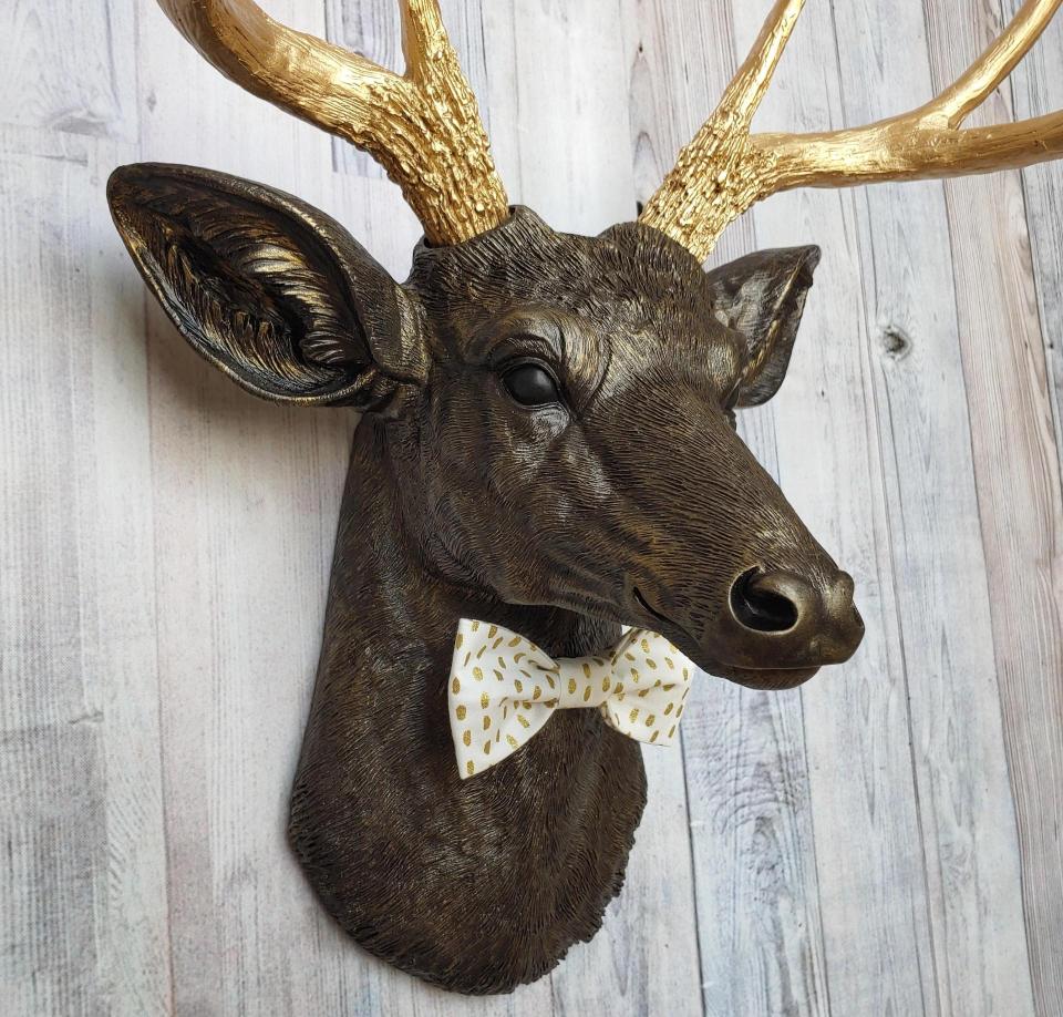 Faux taxidermy rubbed bronze deer head with gold antlers and white and gold polka dot bow tie