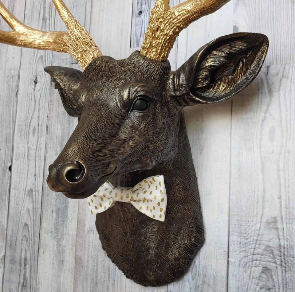 Faux taxidermy rubbed bronze deer head with gold antlers and white and gold polka dot bow tie