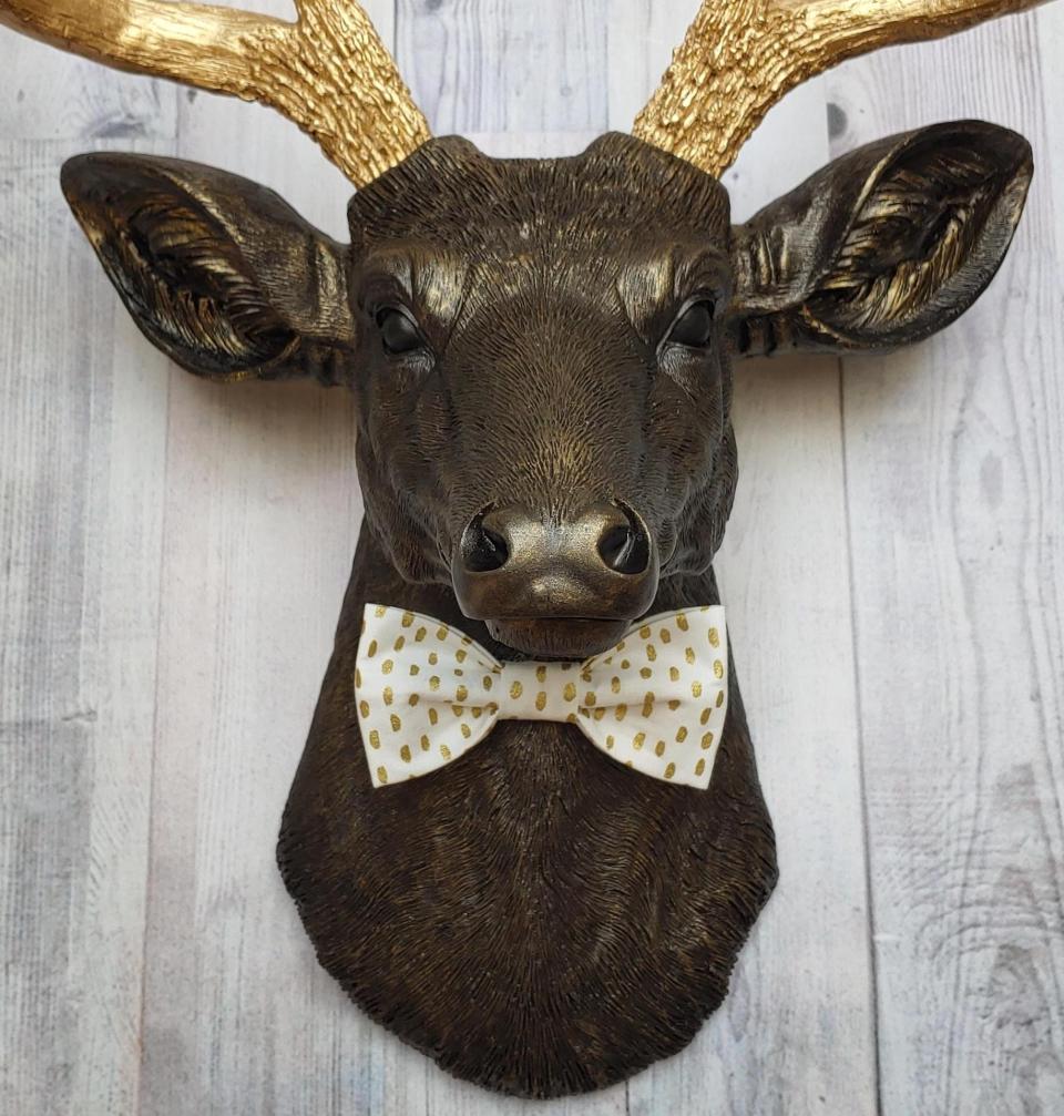 Faux taxidermy rubbed bronze deer head with gold antlers and white and gold polka dot bow tie