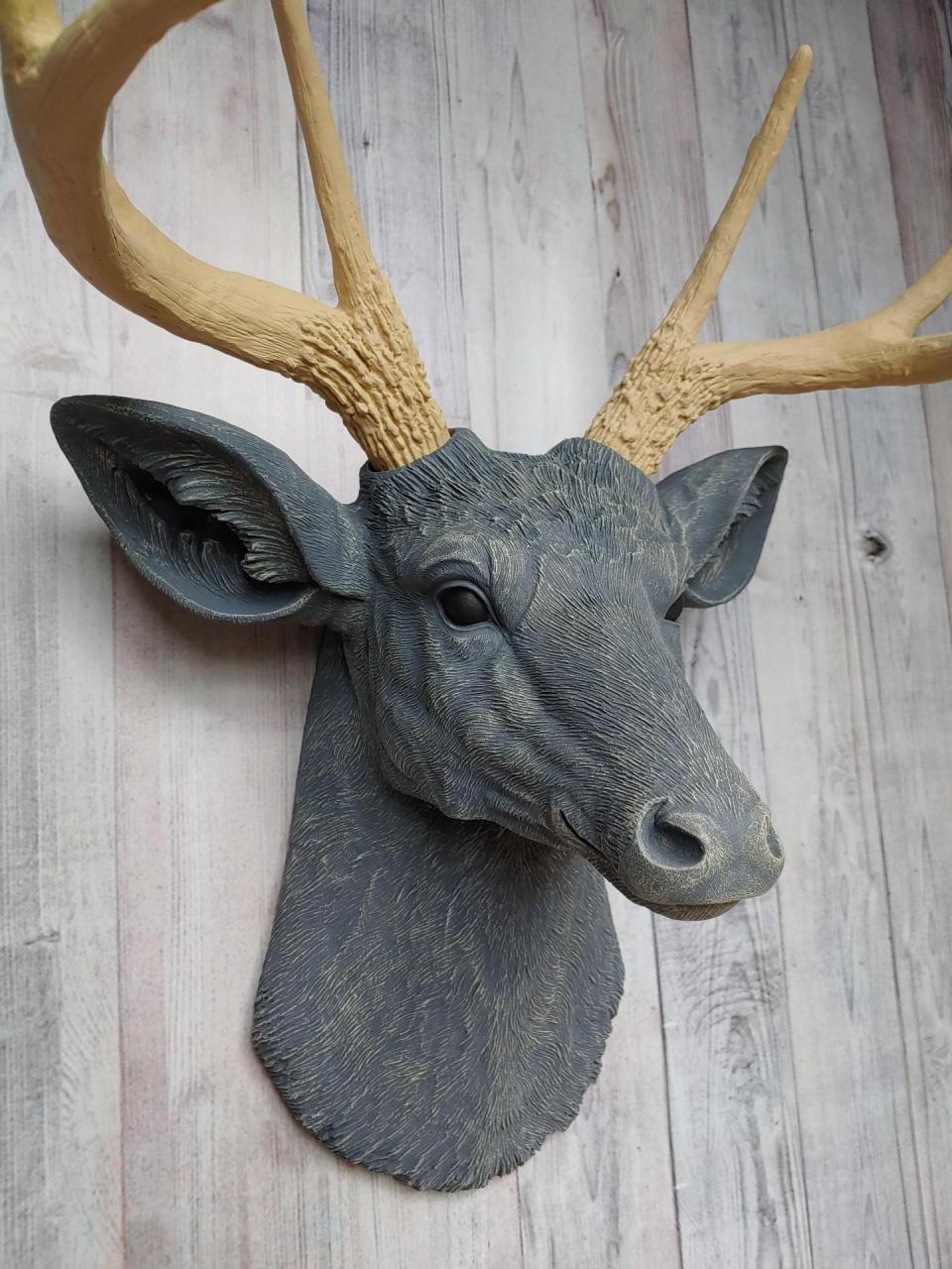 Faux taxidermy deer head that's been painted slate grey with desert sand color accents. The antlers have been painted desert sand.