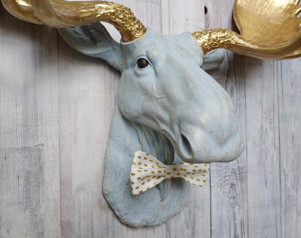 Faux taxidermy moose head painted winter blue with gold antlers with a white and gold polka dot bow tie.