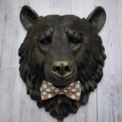 Faux taxidermy bear head wall mount, painted black with gold accenting. A brown and blue polka dot fabric bow tie accents the bears neck